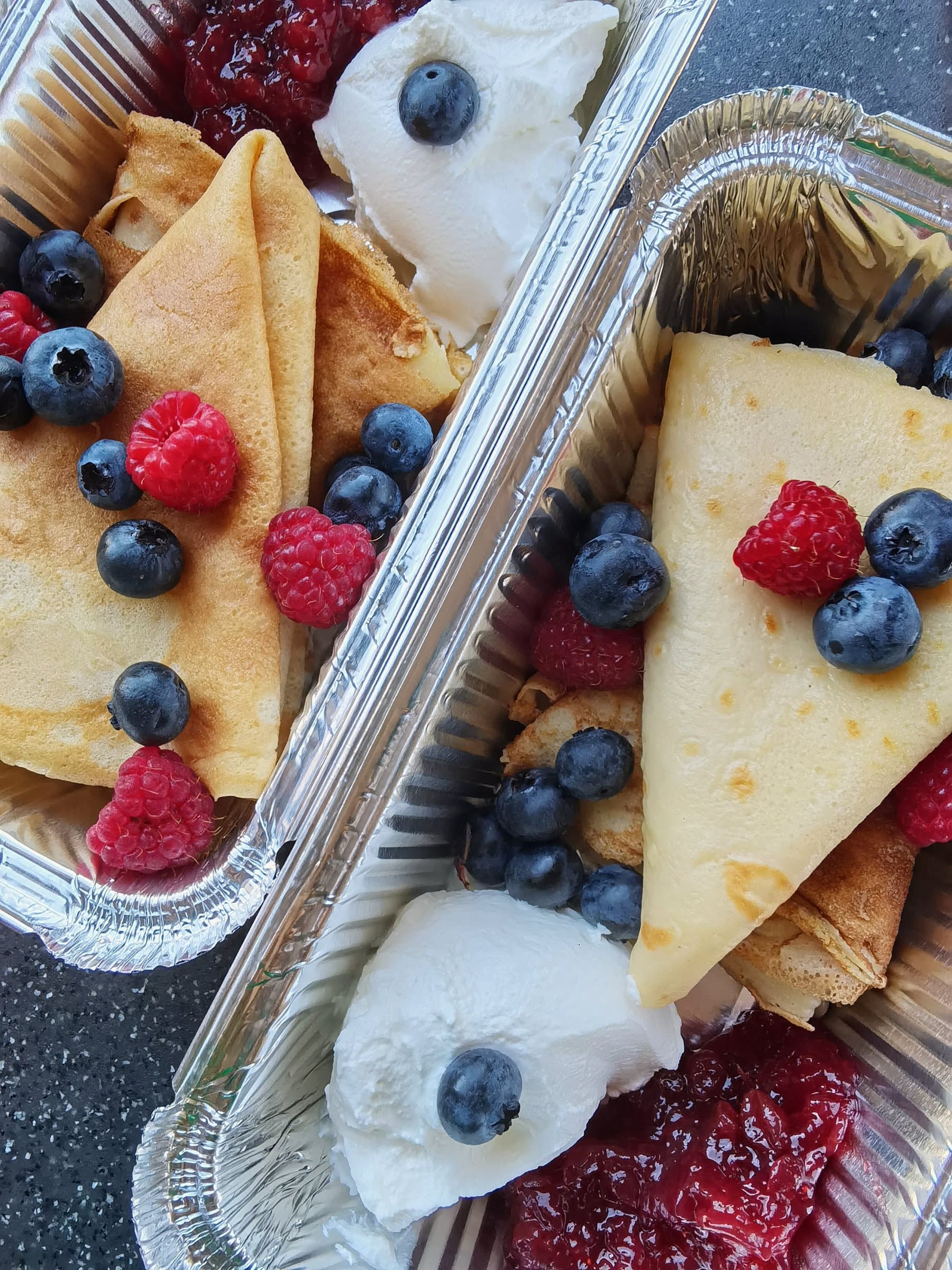Crepes filled with blueberries, raspberries, and whipped cream in a foil tray, prepared during a Wayfarer Zuevcheff cooking session