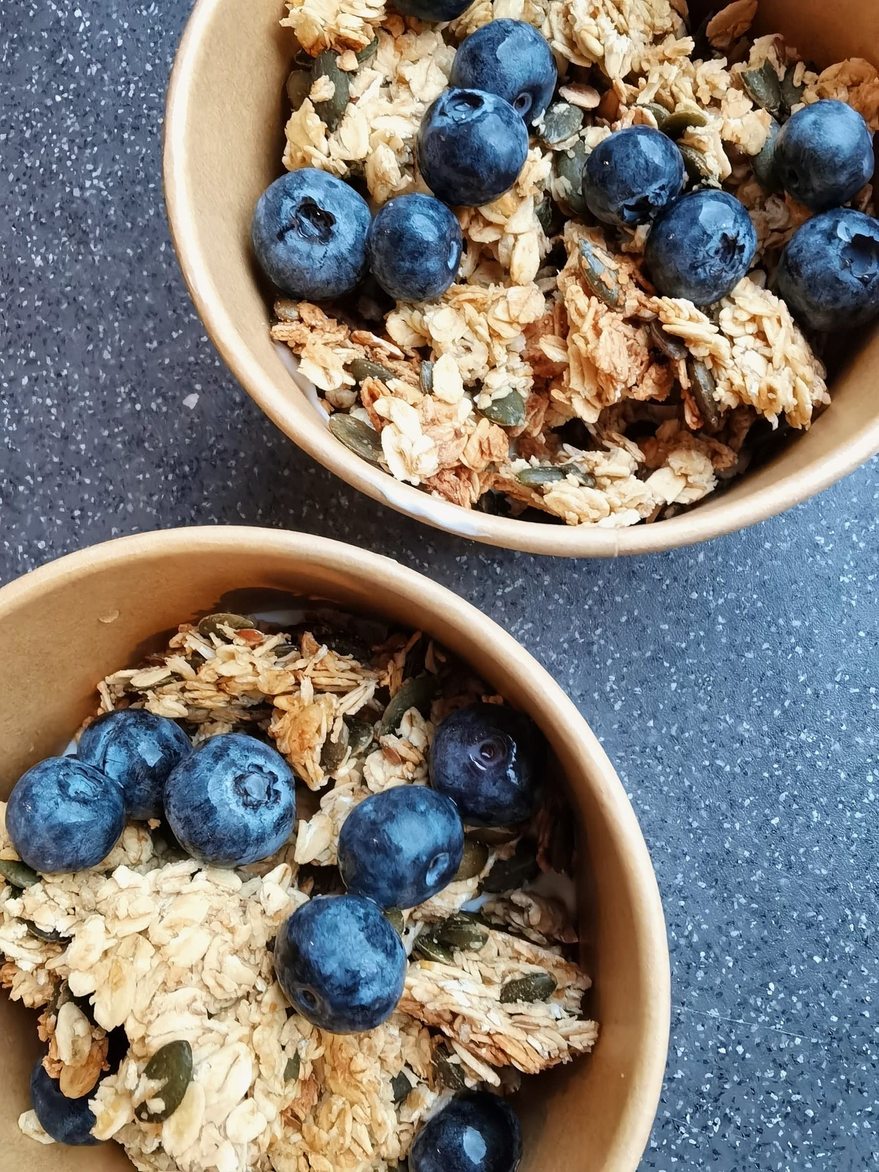 Granola with fresh blueberries served in paper bowls