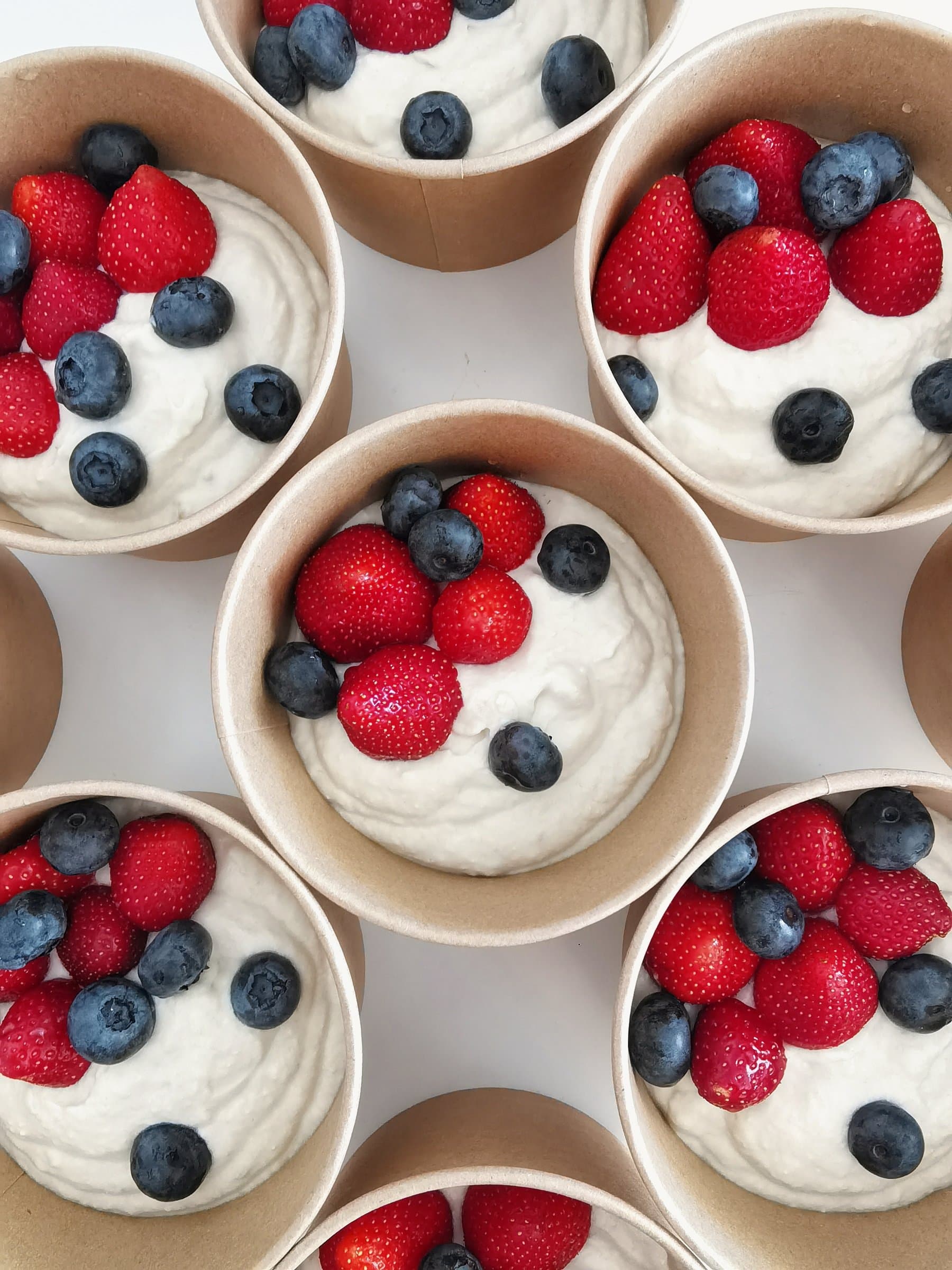 Ricotta cream with strawberries and blueberries, portioned into individual paper cups